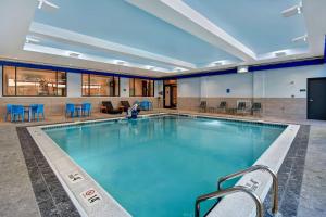 a large swimming pool with blue chairs and tables at Hilton Garden Inn Kalamazoo Downtown in Kalamazoo