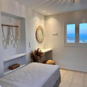 a white bedroom with a bed and a window at Pytilia in Agiassos
