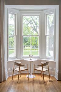 una mesa y 2 sillas en una habitación con ventanas en The CAPE, en Picton