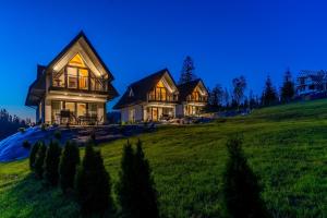 a large house on a grassy hill at night at Smrekowa Ostoja in Poronin