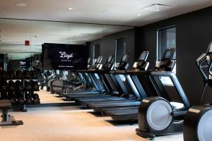 a gym with rows of treadmills and a flat screen tv at The Lloyd Stamford, Tapestry Collection by Hilton in Stamford