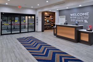 a store lobby with a welcome to the show we share at Hampton Inn Kansas City Northeast in Kansas City