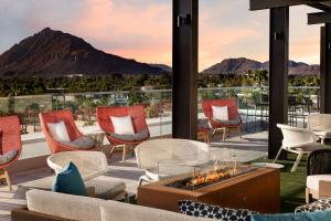 a patio with chairs and a fire pit with mountains in the background at Canopy By Hilton Scottsdale Old Town in Scottsdale