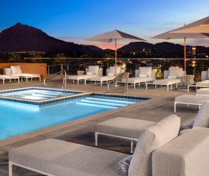 - une piscine avec des chaises longues et des tables dans un bâtiment dans l'établissement Canopy By Hilton Scottsdale Old Town, à Scottsdale