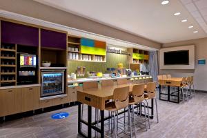 ein Restaurant mit einer Bar mit Stühlen und einem TV in der Unterkunft Home2 Suites By Hilton Barstow, Ca in Barstow