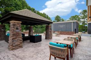 un patio con mesas y sillas y una chimenea de piedra. en Homewood Suites Newport News - Yorktown by Hilton, en Newport News