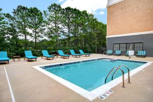 a swimming pool with blue lounge chairs next to a building at Homewood Suites Newport News - Yorktown by Hilton in Newport News