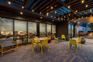 a patio with yellow chairs and tables and windows at Home2 Suites Corona, Ca in Corona