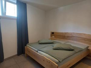 um quarto com uma cama de madeira e uma janela em Hiša za Gradom em Kobarid