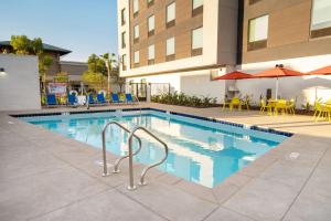 a swimming pool with chairs and umbrellas next to a building at Home2 Suites Corona, Ca in Corona