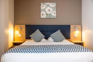 a bedroom with a bed with blue and white pillows at Hôtel Le Bastia in Bastia