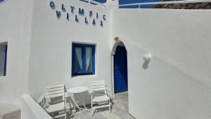 d'une terrasse avec des chaises, une table et une porte bleue. dans l'établissement Olympic Villas, à Oia
