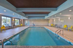 a pool in a hotel with yellow chairs and tables at Home2 Suites By Hilton Savannah Midtown, Ga in Savannah