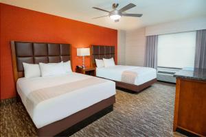 two beds in a hotel room with orange walls at Homewood Suites by Hilton Baltimore - Arundel Mills in Hanover
