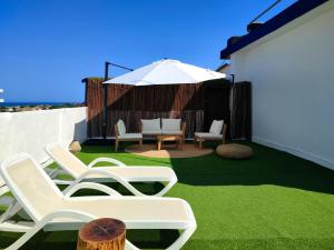 eine Terrasse mit zwei Stühlen, einem Sonnenschirm und Rasen in der Unterkunft Hotel Porto in Gandía