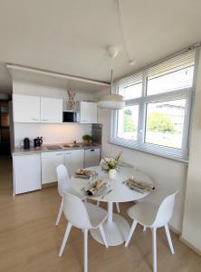 a white kitchen with a white table and chairs at Pools, Sauna und Balkon mit Panoramablick in Sankt Englmar
