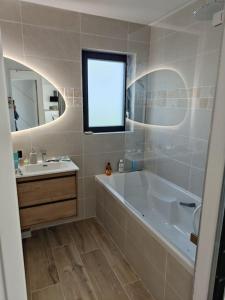 uma casa de banho com uma banheira, um lavatório e um espelho. em Maison neuve proche du centre em Pabu
