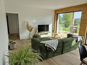 uma sala de estar com um sofá verde e uma televisão em Maison neuve proche du centre em Pabu