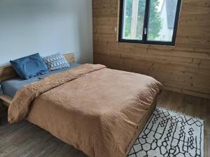 um quarto com uma cama com um cobertor e uma janela em Maison neuve proche du centre em Pabu