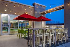 een patio met tafels en stoelen en rode parasols bij Home2 Suites By Hilton Lexington Hamburg in Lexington