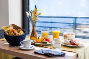un tavolo con colazione a base di pane tostato, frutta e succo d'arancia di Hôtel Le Bastia a Bastia