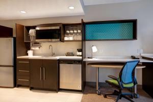 a kitchen with a sink and a desk with a chair at Home2 Suites By Hilton Lexington Hamburg in Lexington