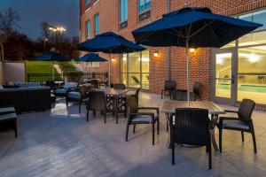 un patio con mesas, sillas y sombrillas azules en Hilton Garden Inn Hanover Arundel Mills, MD en Hanover
