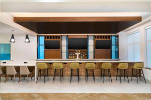 a large kitchen with a bar with stools at Hilton Garden Inn Hanover Arundel Mills, MD in Hanover