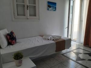 a bed in a white room with a plant on it at Atalos Suites in Kamari