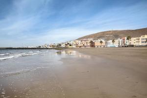 a sandy beach with buildings and the ocean at Apartamento Las Palmeras in Gran Tarajal