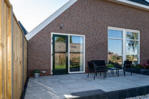 een patio met stoelen en een tafel naast een bakstenen gebouw bij Boerderijkamer de Hooizolder in Wijhe