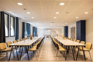 una sala conferenze con tavoli, sedie e lavagna bianca di Hôtel Le Bastia a Bastia