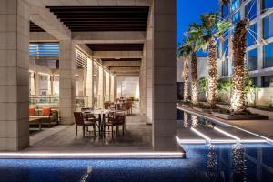 リヤドにあるDoubleTree Suites by Hilton - Riyadh Financial Districtのホテルのロビーにはヤシの木があり、テーブルと椅子が備わります。