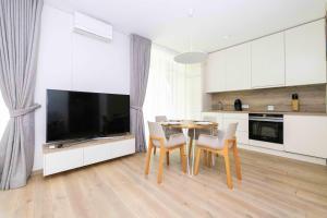 cocina con mesa y sillas y TV en Vanagupes Park Apartment, By Cohost en Palanga
