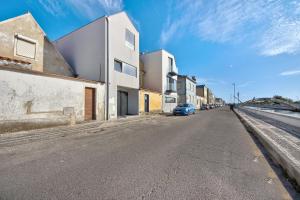 an empty street with buildings and a blue car on the road at Apartamento T1 - Salina Ria in Aveiro