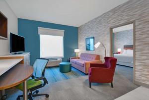Habitación de hotel con cama, escritorio y sillas en Home2 Suites by Hilton Fort Myers Colonial Blvd, en Fort Myers