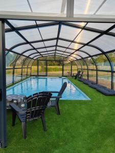 a swimming pool in a glass greenhouse with chairs in the grass at Chambres d' Hôtes des Glands ' heures in Saint-Martin-de-Gurçon