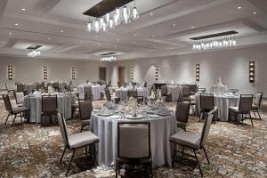 uma sala de banquetes com mesas, cadeiras e lustres em Hilton Garden Inn Camden Waterfront Philadelphia em Camden