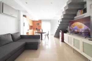 sala de estar con sofá y TV en Sand Bay Beach Duplex, en Girona