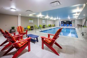 una piscina con sillas, una mesa y una piscina en Home2 Suites By Hilton Lewisburg, Wv, en Lewisburg