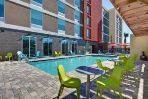 a pool with tables and chairs next to a building at Home2 Suites By Hilton Largo, Fl in Largo