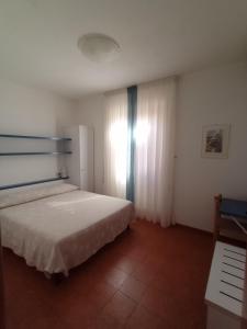 een slaapkamer met een wit bed en een raam bij B&B da AnnaMaria in Chiessi