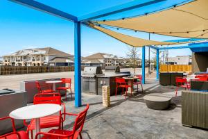 a patio with red chairs and tables and a blue canopy at Tru By Hilton Midland, Tx in Midland