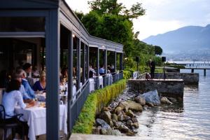 a restaurant with people sitting at tables next to a river at Bella Hotel & Restaurant with private dock for mooring boats in San Felice del Benaco