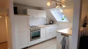 a kitchen with white cabinets and a sink and a window at Ferienwohnung Achterdeck - Alte Schmiede Neugarmssiel in Wangerland