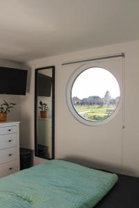 um quarto com uma cama e uma janela redonda em Hausboot Wangermeer Nordsonne11 em Wangerland