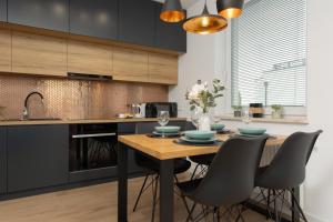 a kitchen with a wooden table and black cabinets at Trendy Warsaw Apartment with 2 Bedrooms, Balcony & Parking by Renters in Warsaw