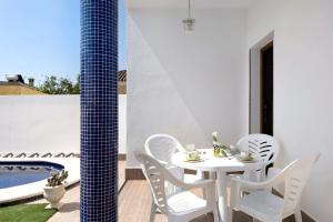 a white table and chairs on a patio with a pool at Casa Cala del Aceite 2 in Conil de la Frontera