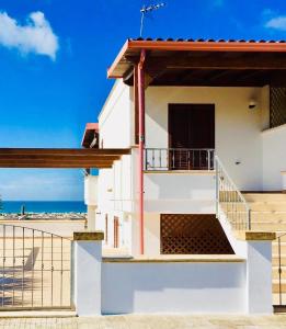 a house with a balcony with the beach in the background at Villa Sole Maldive del Salento in Torre Pali