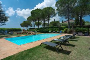 a swimming pool with chaise lounge chairs in the grass at Villa Monte Bottigli in Diaccialone